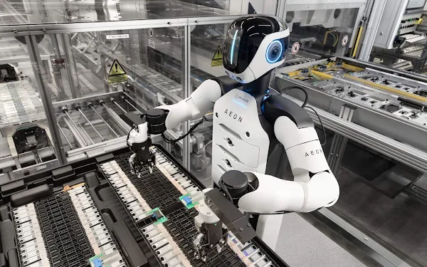 Robô humanoide sendo supervisionado por técnico em linha de produção
