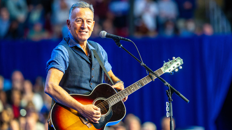 Bruce Springsteen posando ao lado de um veículo clássico