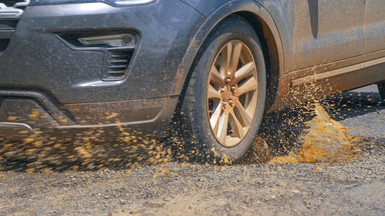 Pessoa verificando o pneu de um carro após atingir um buraco