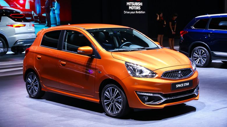 Mitsubishi Mirage 2019, um carro compacto de cor prata, estacionado em uma rua da cidade.