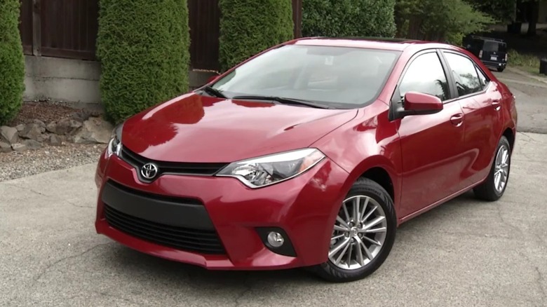 Toyota Corolla LE Eco 2014, um sedã branco de quatro portas, estacionado em uma rua residencial.