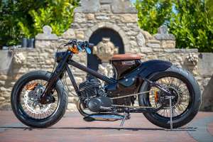 Honda C70 customizada com motor Yamaha DT250MX, exibindo pintura Root Beer candy e chamas fantasma