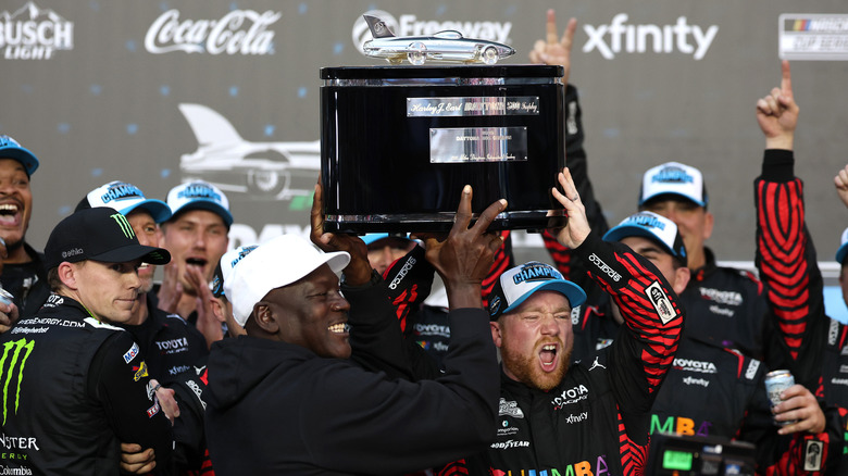 Troféu da vitória da 23XI Racing, com o logo da equipe e da NASCAR ao fundo