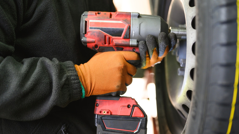 Mecânico utilizando uma chave de torque para apertar parafusos de roda, ilustrando a importância da ferramenta correta.