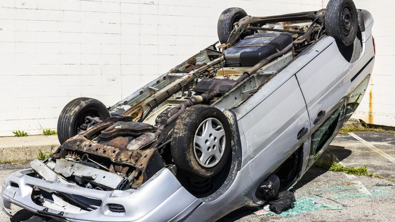 Carro azul amassado na frente após colisão, com pedaços soltos no chão