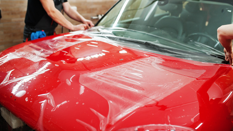 Homem secando o capô de um carro após lavagem, destacando a importância da manutenção do PPF