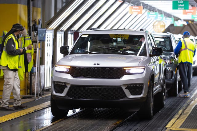 Visão aérea de uma linha de montagem com veículos em produção, simbolizando a indústria automotiva e a força de trabalho.