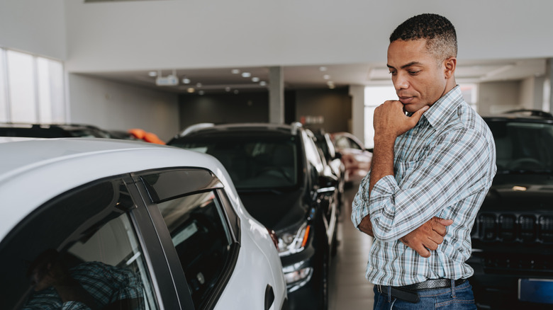Mulher em um carro branco, com um homem ao lado, prestes a fazer um test drive