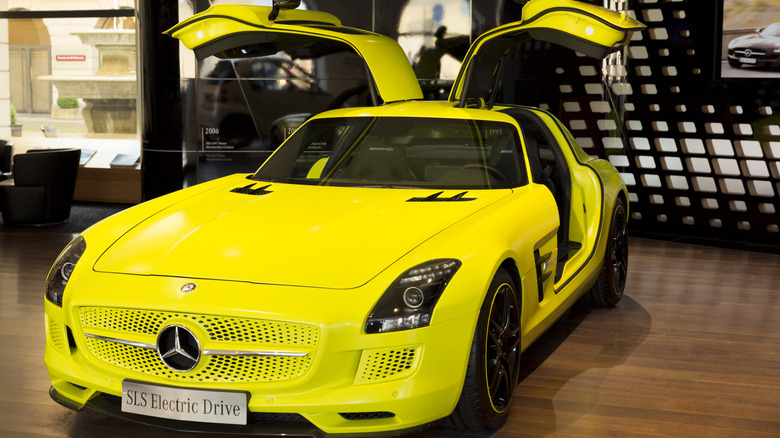 Mercedes-Benz SLS AMG Electric Drive em um azul cromado vibrante, com as portas asa de gaivota abertas, um ícone de design.