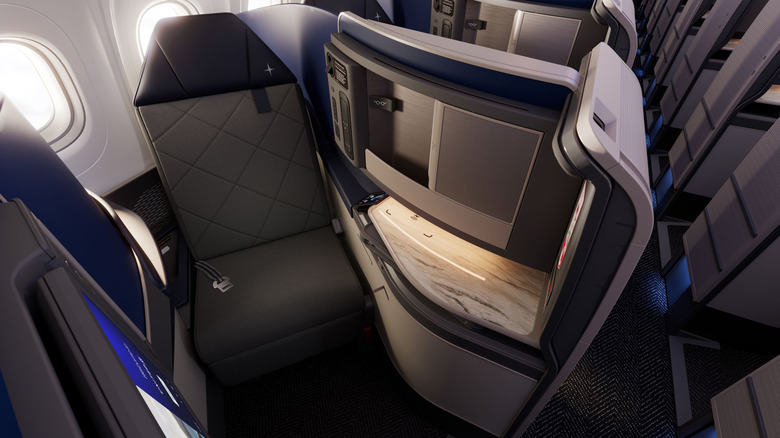 Detalhe da suíte Polaris da United Airlines, mostrando o assento e tela de entretenimento