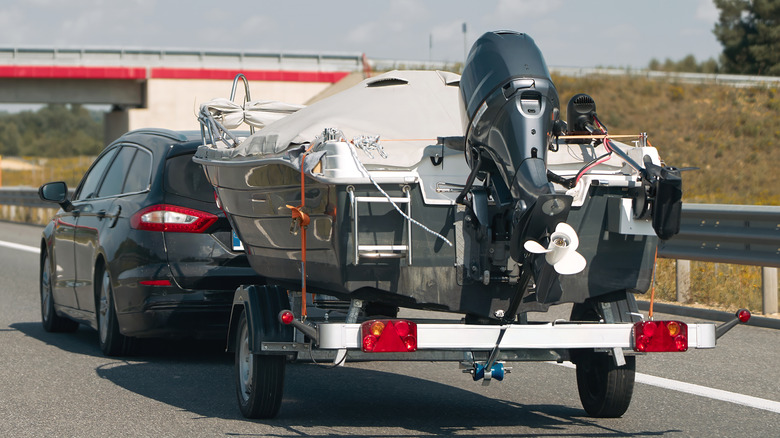 Sedan azul rebocando um pequeno trailer com dois jet skis