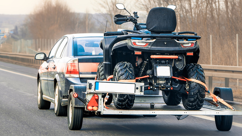 Subaru Crosstrek vermelho rebocando um trailer pequeno em uma estrada